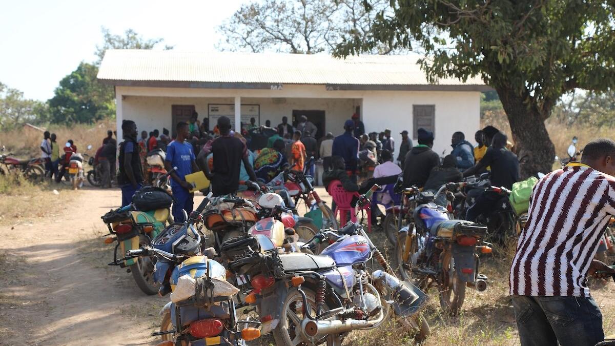 Un groupe de personnes et leurs motos sont photographiés devant un bâtiment.