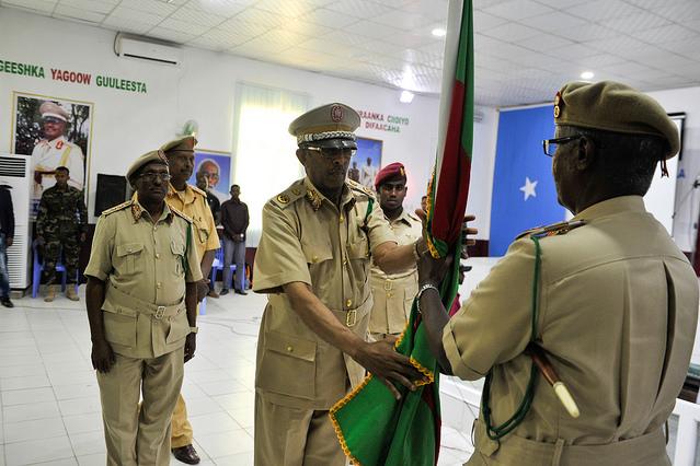 Men in uniform stand with a flag